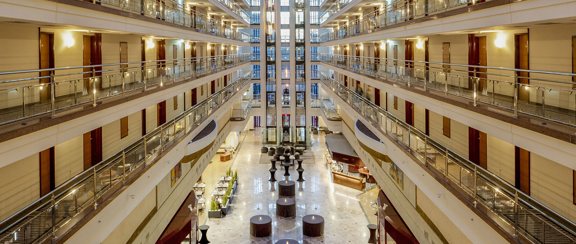 Impressionante hall dell'hotel con soffitto di vetro, più piani e aree salotto, che crea un ambiente spazioso ed elegante
