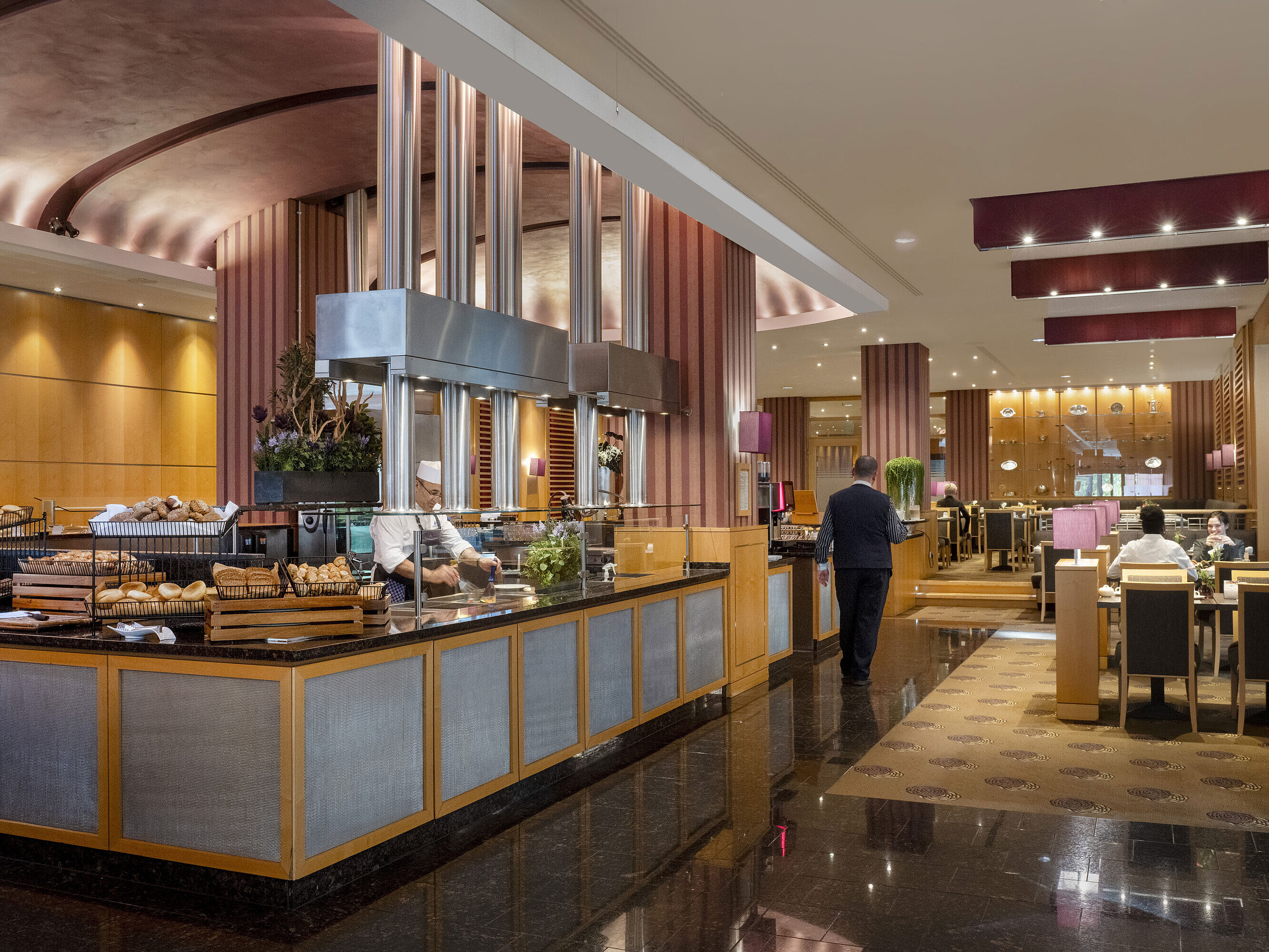 Area colazione al Maritim Hotel Düsseldorf con stazione di cucina live, prodotti da forno freschi e interni eleganti.