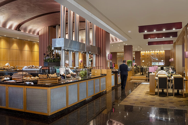 Zona de desayuno en el Hotel Maritim Düsseldorf con estación de cocina en vivo,pan recién horneado y diseño interior elegante