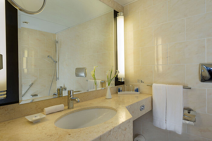 Bagno moderno al Maritim Hotel Fulda con lavabo in marmo, grande specchio e doccia walk-in.