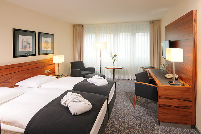 Habitación doble luminosa con escritorio, sillones y albornoces en Maritim Hotel Múnich