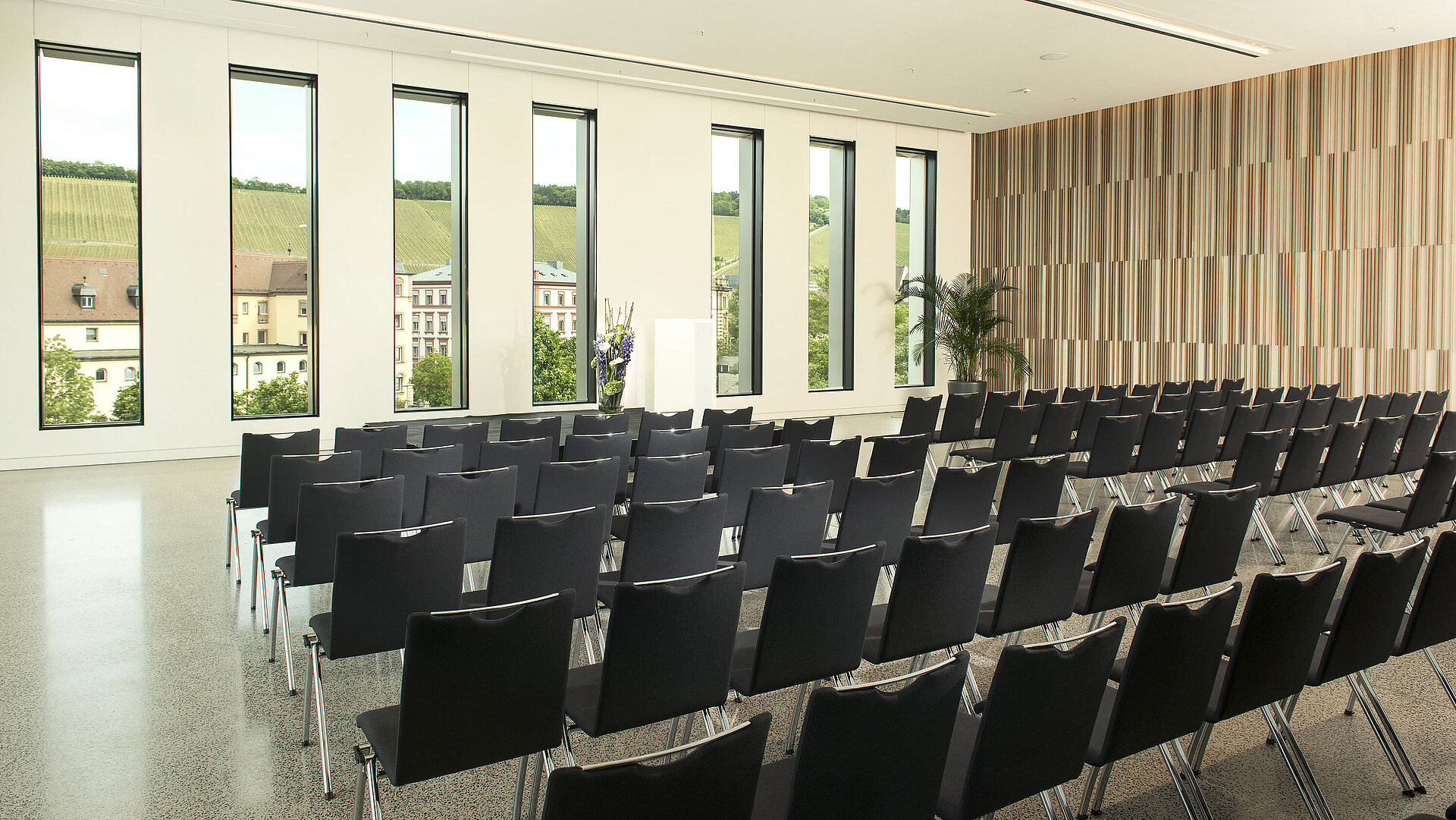 Sala de eventos moderna del Maritim Hotel Würzburg con vista a viñedos y grandes ventanales