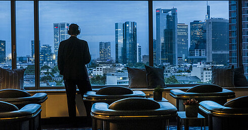 Ospite che ammira la vista panoramica dello skyline di Francoforte dalla Sky Lounge del Maritim Hotel Frankfurt.
