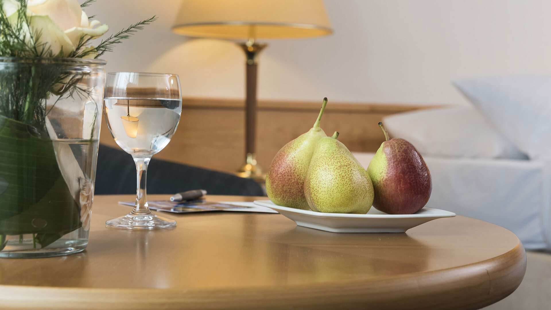 Table with a plate full of fresh fruit and a glass of water.