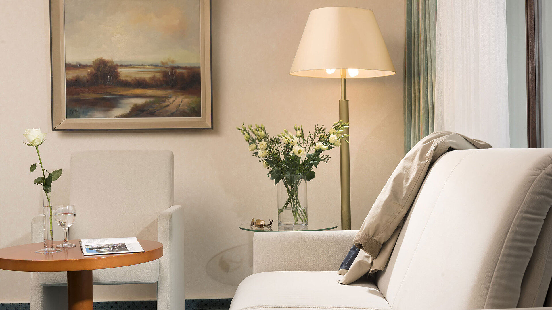 Bright living area at Maritim Hotel Bad Salzuflen with flowers, painting and cosy seating