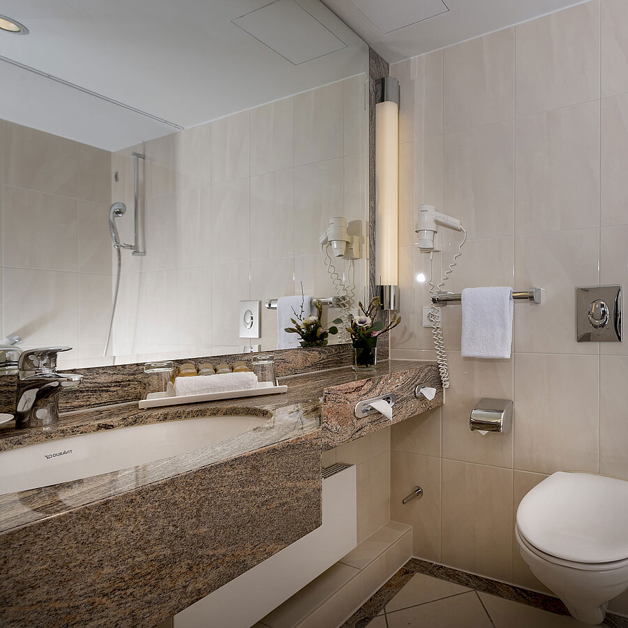 Bagno moderno al Maritim Seehotel Timmendorfer Strand con lavabo, specchio, doccia, WC e vasca.
