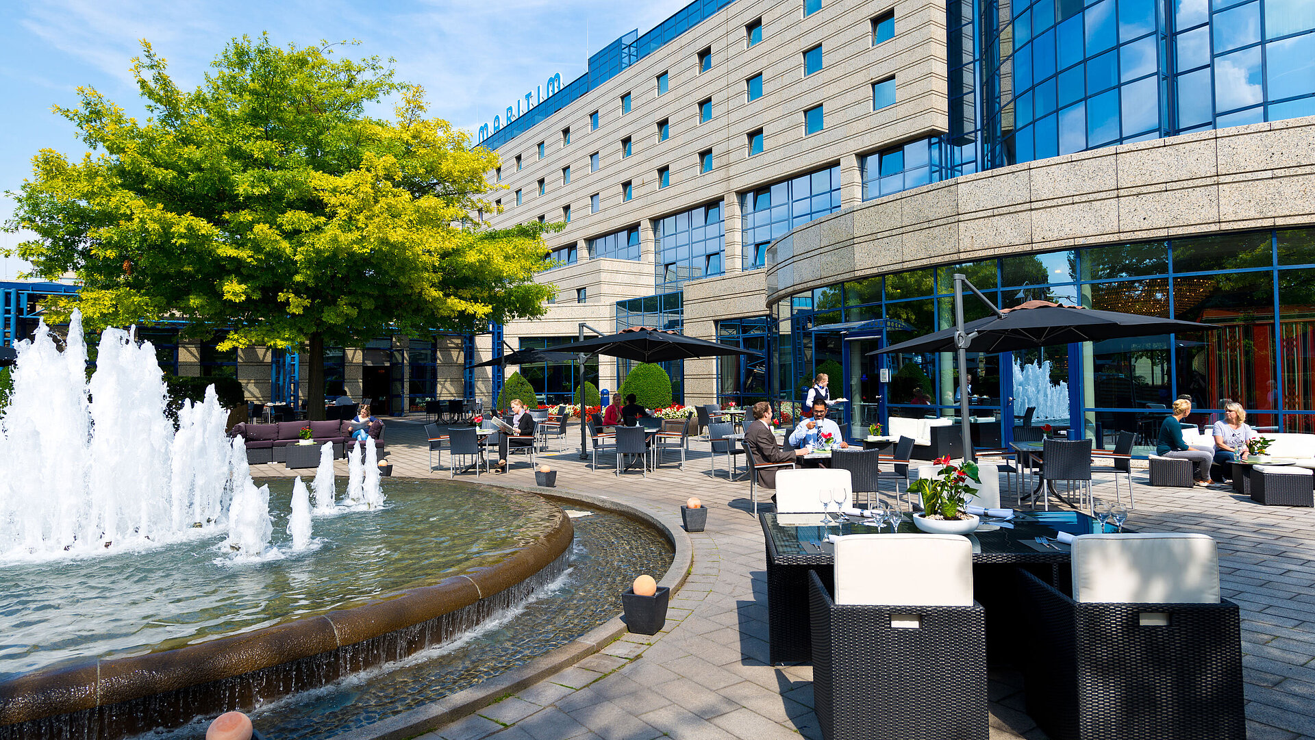 Terrace of the Maritim Hotel Bonn with seating areas, fountain, and guests dining and relaxing outdoors.
