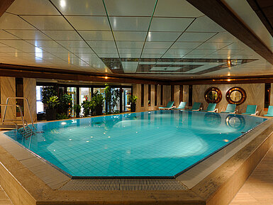 Indoor pool at Maritim Hotel Cologne with loungers and plants for a relaxing atmosphere.