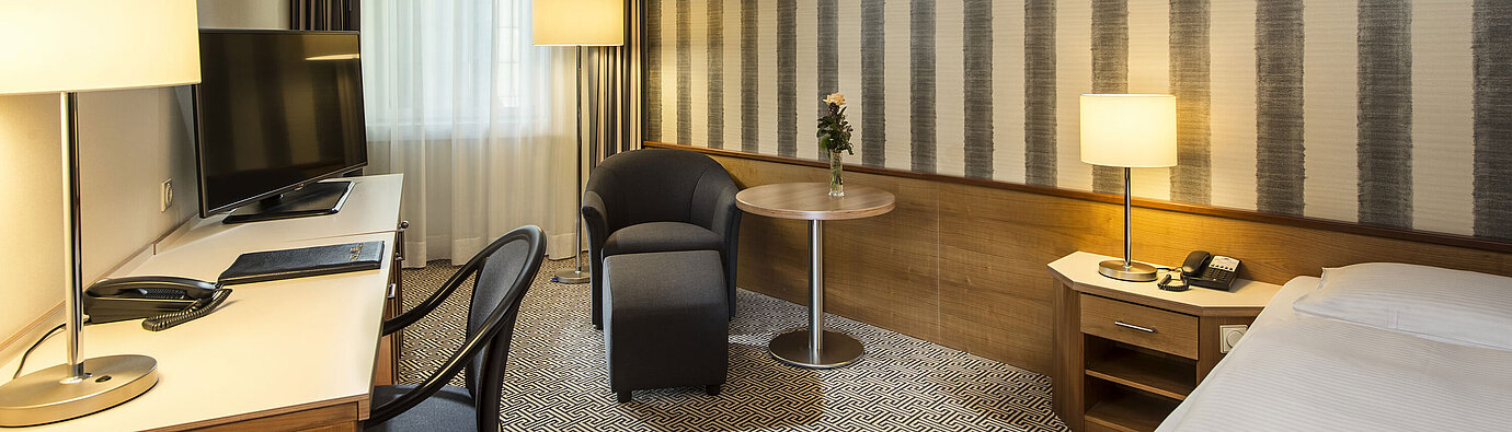 	Desk with TV and comfortable seating in single room at Maritim Hotel Stuttgart