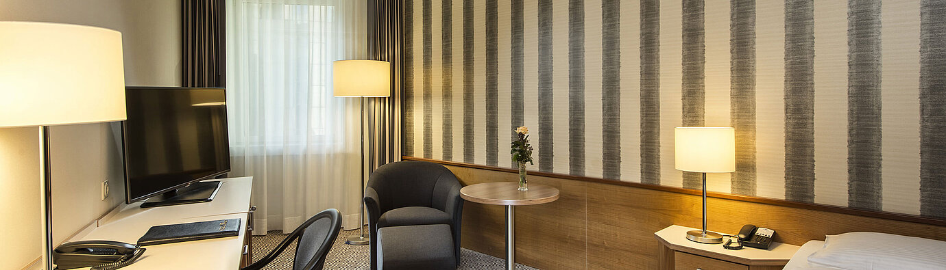 	Desk with TV and comfortable seating in single room at Maritim Hotel Stuttgart