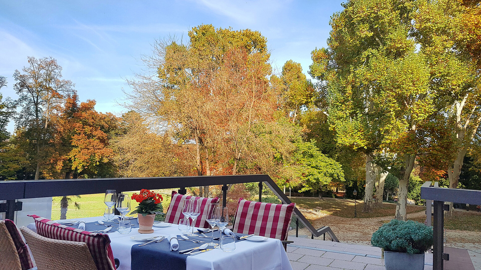 Autumn terrace at Maritim Hotel Bad Homburg with colorful trees and elegantly set table.