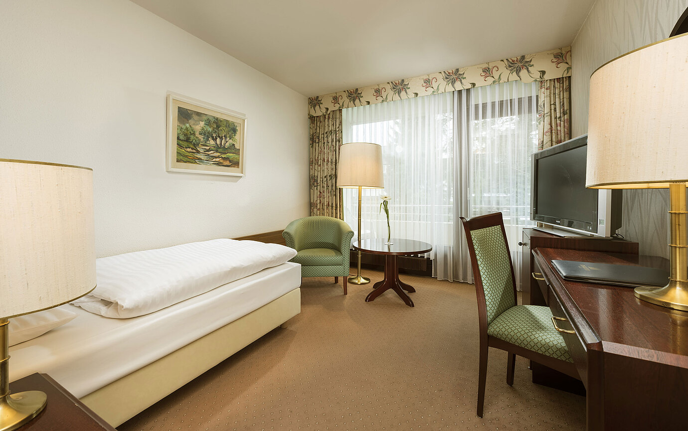 Camera con poltrona, scrivania e balcone al Maritim Hotel Bad Salzuflen