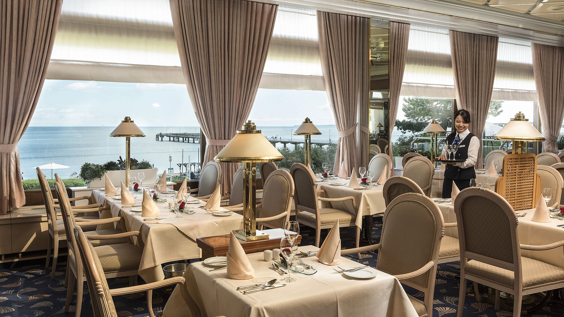 Elegant restaurant with sea view and set tables at Maritim Seehotel Timmendorfer Strand.