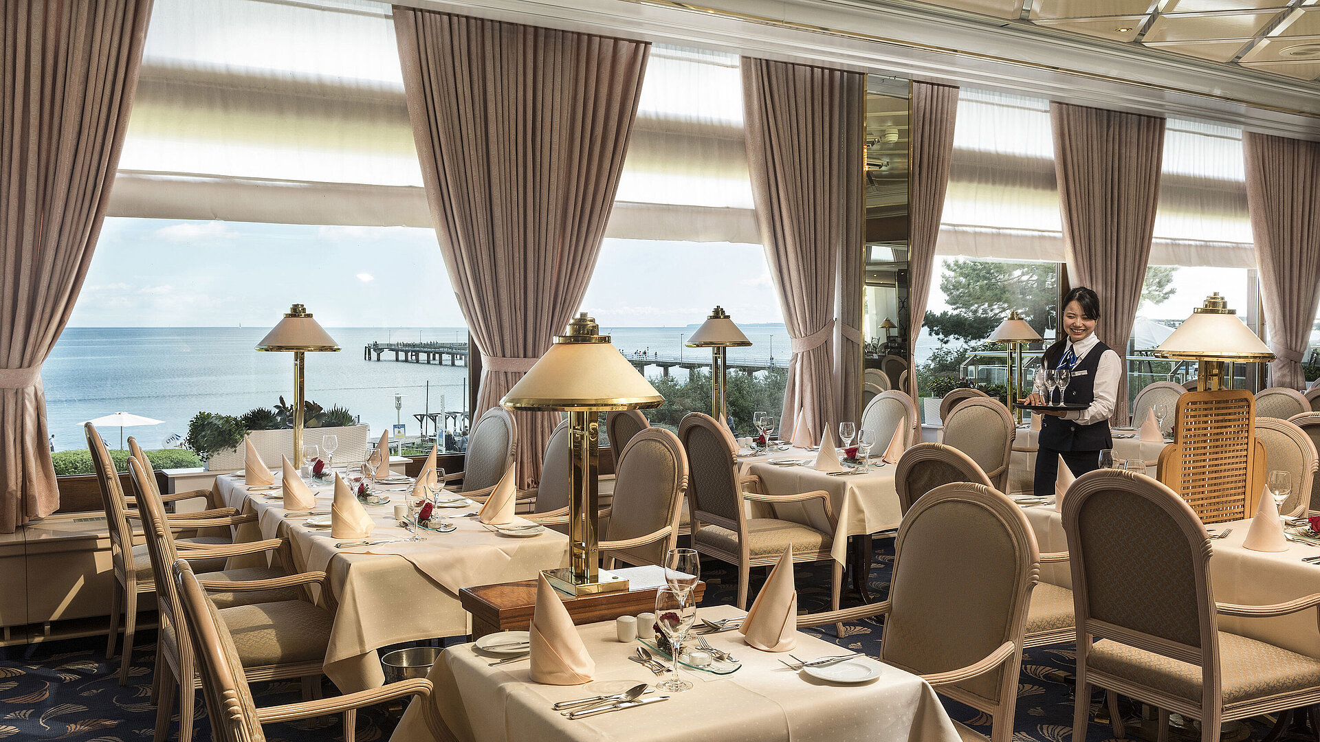 Elegant restaurant with sea view and set tables at Maritim Seehotel Timmendorfer Strand.