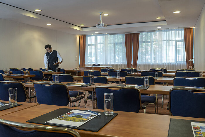 Salle de réunion lumineuse au Maritim Hotel Magdeburg avec sièges en rangée, lumière naturelle et équipement moderne.