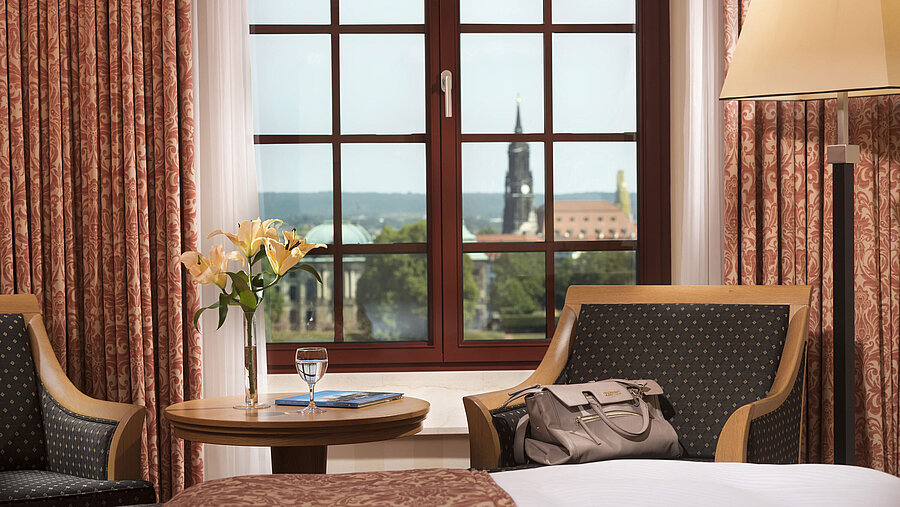 Coin salon dans la chambre supérieure de l'hôtel Maritim de Dresde avec vue sur la vieille ville historique depuis la fenêtre