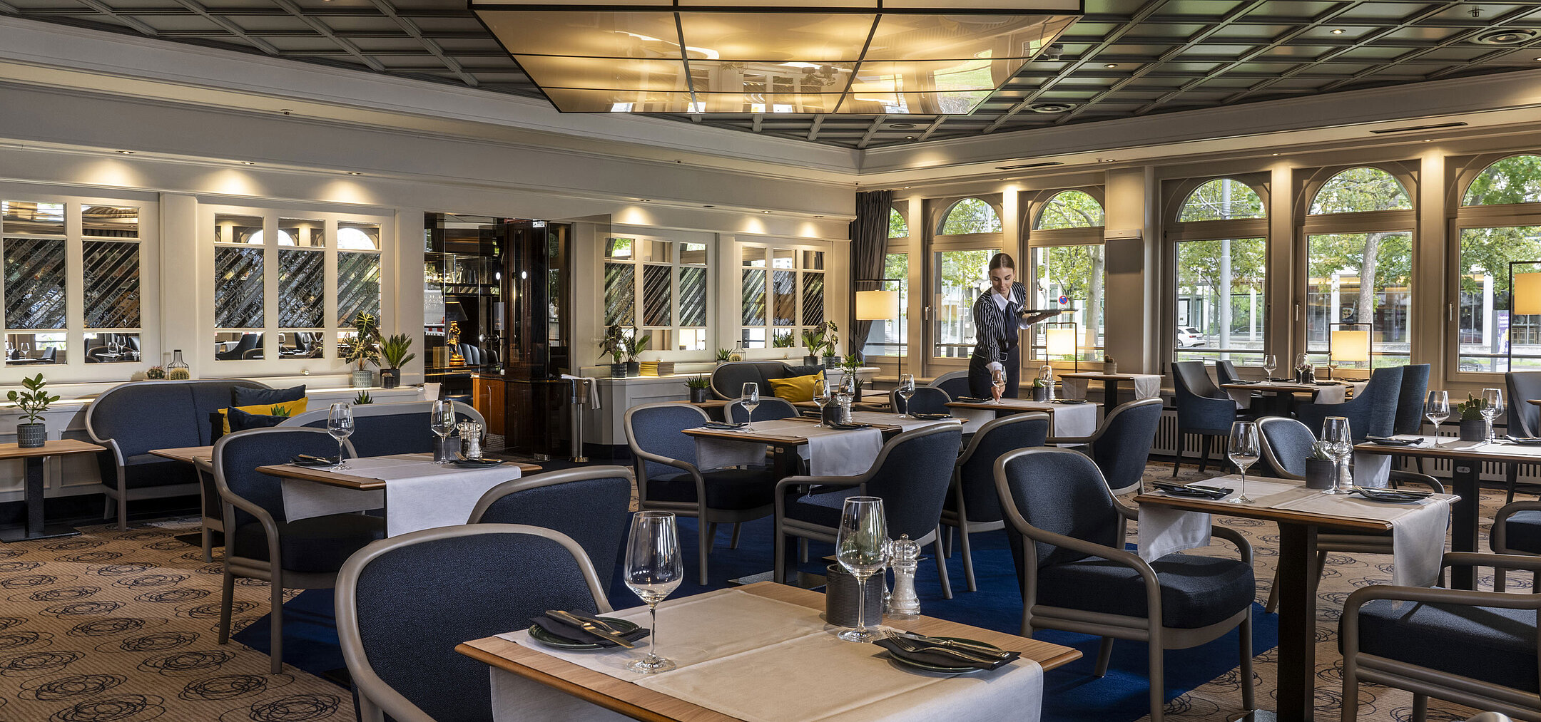 Ristorante Ristorante moderno del Maritim Darmstadt con tavoli apparecchiati e design elegante.Un membro del personale offre il servizio