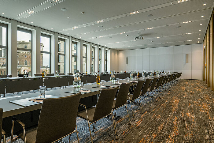 Salle de réunion moderne à l'hôtel Maritim Ingolstadt avec grandes fenêtres, sièges en U et équipement professionnel.