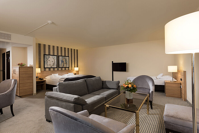 Camera famigliari Suite spaziosa del Maritim Hotel Königswinter con area salotto e design elegante.