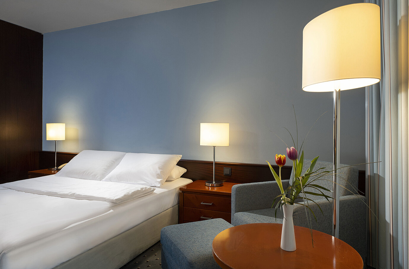Habitación individual cómoda con cama queen-size, muebles modernos y luz ambiental en el Maritim Hotel Darmstadt.