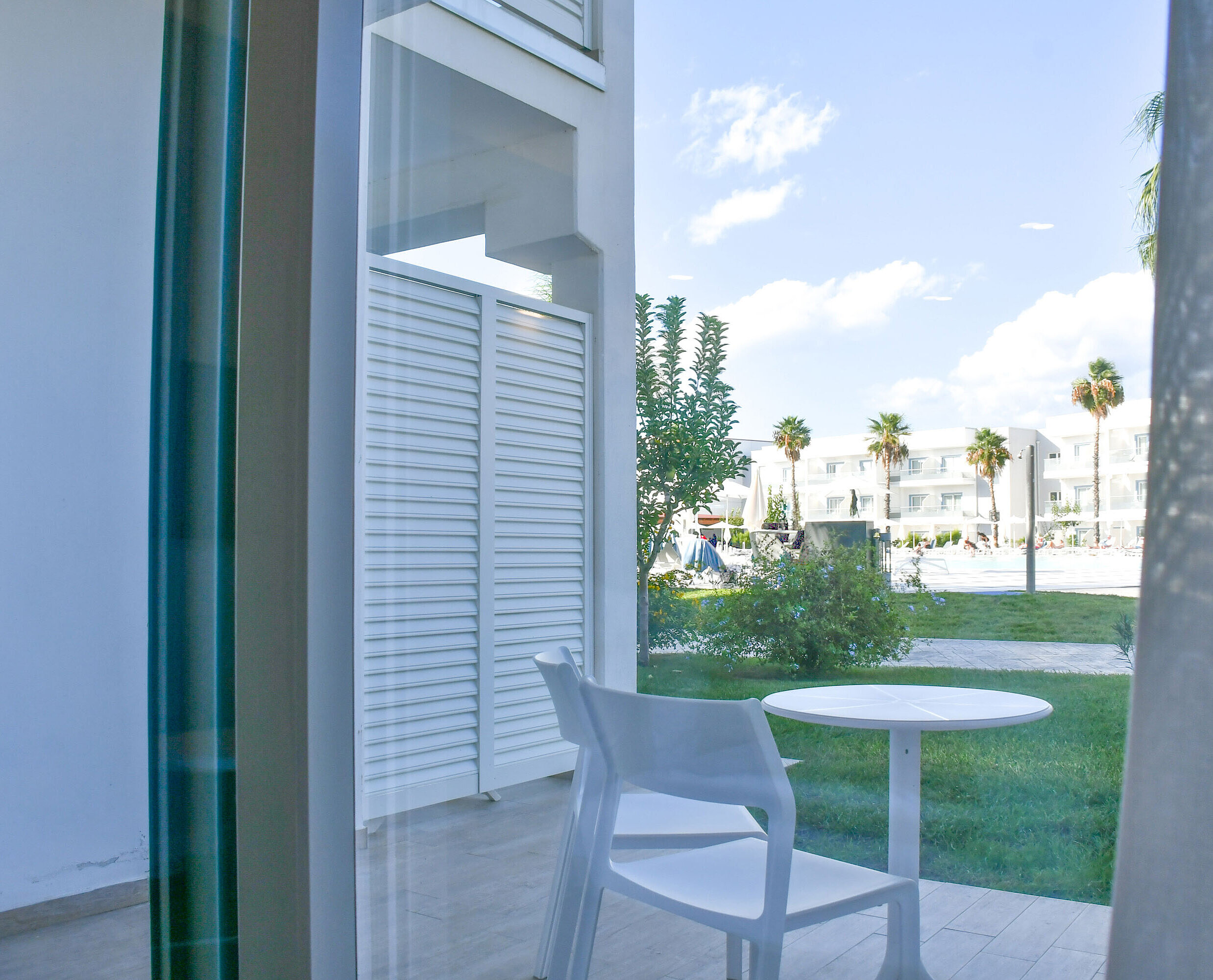 Terrazza privata con tavolo e sedie al Maritim Resort Calabria con vista su giardino e piscina