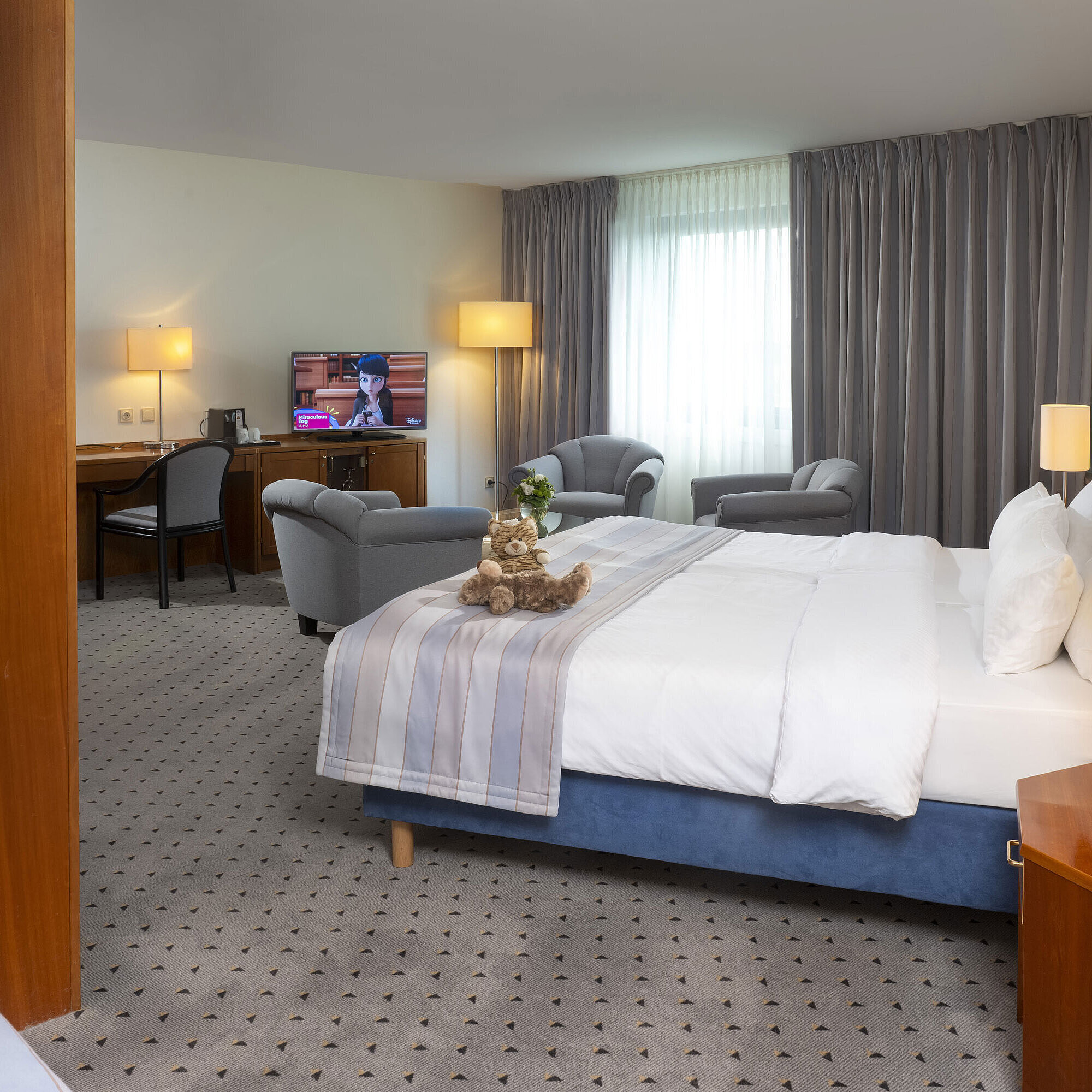 Habitación famiglia Superior Habitación espaciosa en Maritim Hotel Hannover con cama doble, área de descanso y TV.