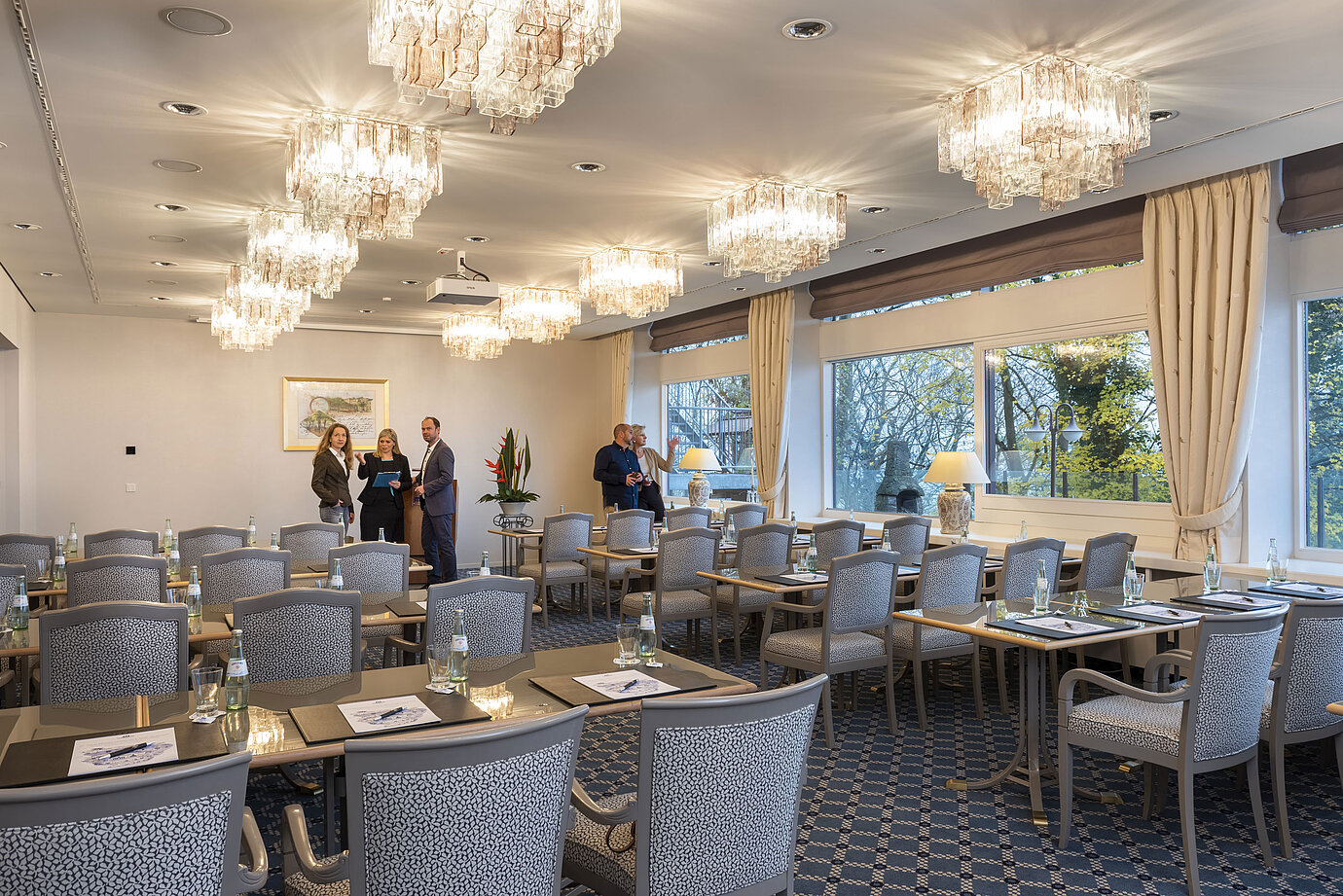 Il Salon Copenhagen del Maritim Hotel Kiel è un'elegante sala conferenze con lampadari, tavoli apparecchiati e grandi finestre.