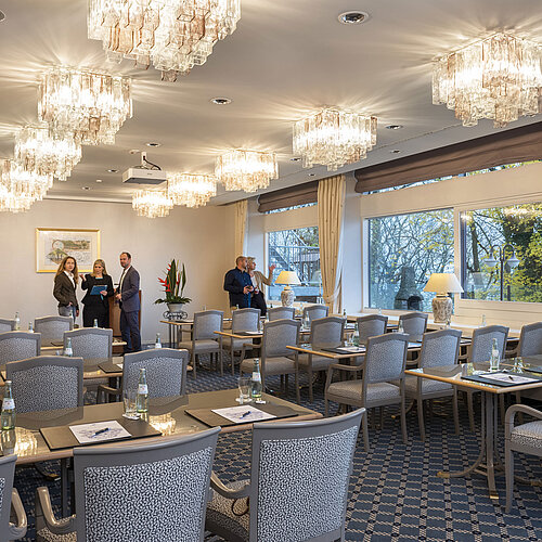 El Salón Copenhague del Maritim Hotel Kiel es una elegante sala de conferencias con lámparas de araña, mesas tendidas y grandes ventanales.