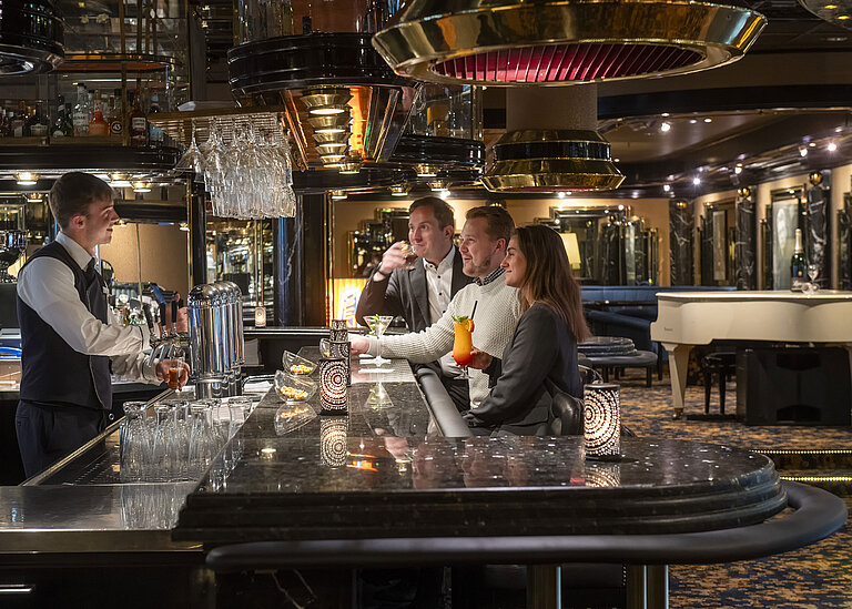 Los huéspedes disfrutan de cócteles en el piano bar del Hotel Maritim Colonia, mientras el camarero los atiende.