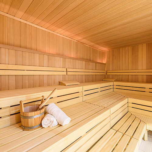 Sauna accogliente con panche in legno, secchio da sauna e asciugamano, ideale per il relax al Maritim Hotel Bremen.