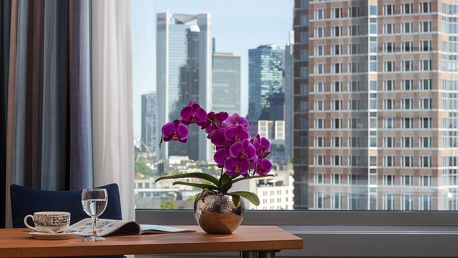 Vista dalla camera del Maritim Hotel Frankfurt con panorama skyline, scrivania e orchidea elegante.