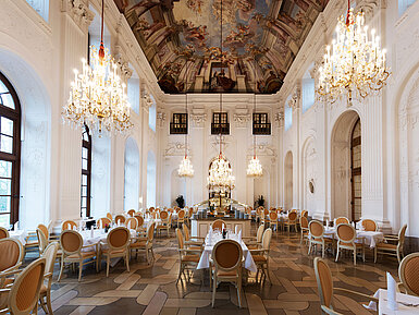 Elegant Apollo Hall at Maritim Hotel Fulda with chandeliers, fresco ceiling, and stylishly set tables.