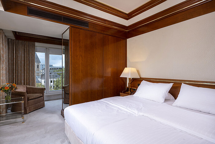 Bright bedroom in the Heumarkt Suite at Maritim Hotel Cologne featuring a cozy double bed, wood accents, and balcony access.