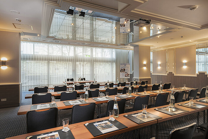 Sala con ventanales, mesas y botellas de agua en el Maritim Hotel Múnich