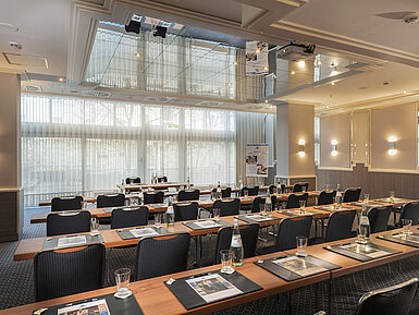 Sala con ventanales, mesas y botellas de agua en el Maritim Hotel Múnich