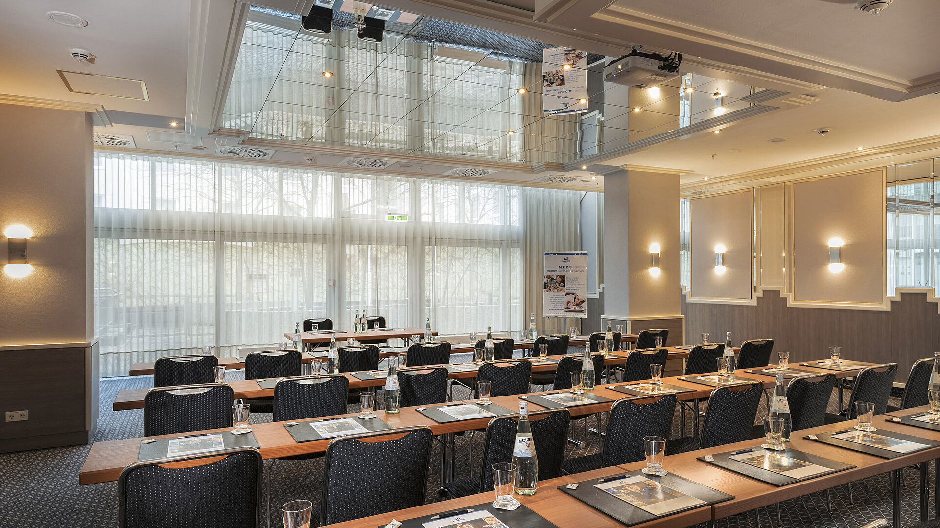 Sala con ventanales, mesas y botellas de agua en el Maritim Hotel Múnich