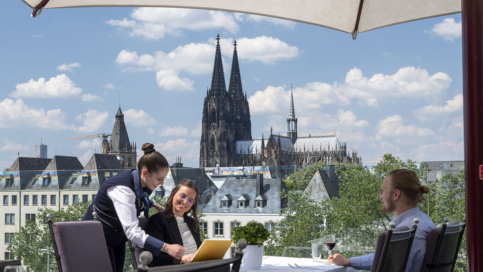 Ospiti godono del servizio sulla terrazza panoramica dell'Hotel Maritim Colonia con vista sul Duomo di Colonia.