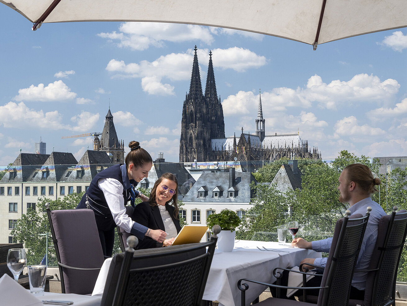 Ospiti godono del servizio sulla terrazza panoramica dell'Hotel Maritim Colonia con vista sul Duomo di Colonia.