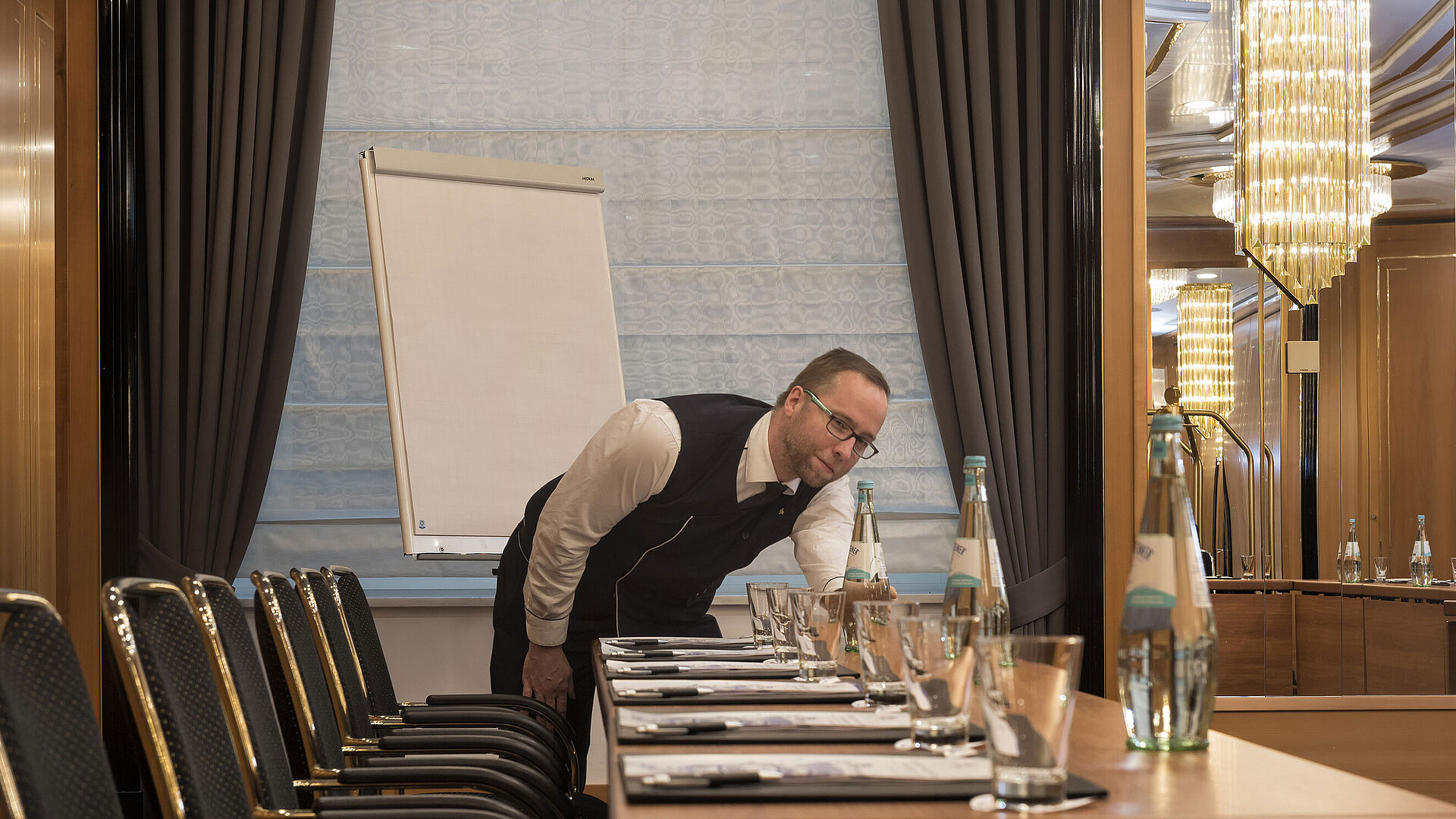 Employé préparant la table avec bouteilles d'eau et verres au Maritim Hotel Stuttgart