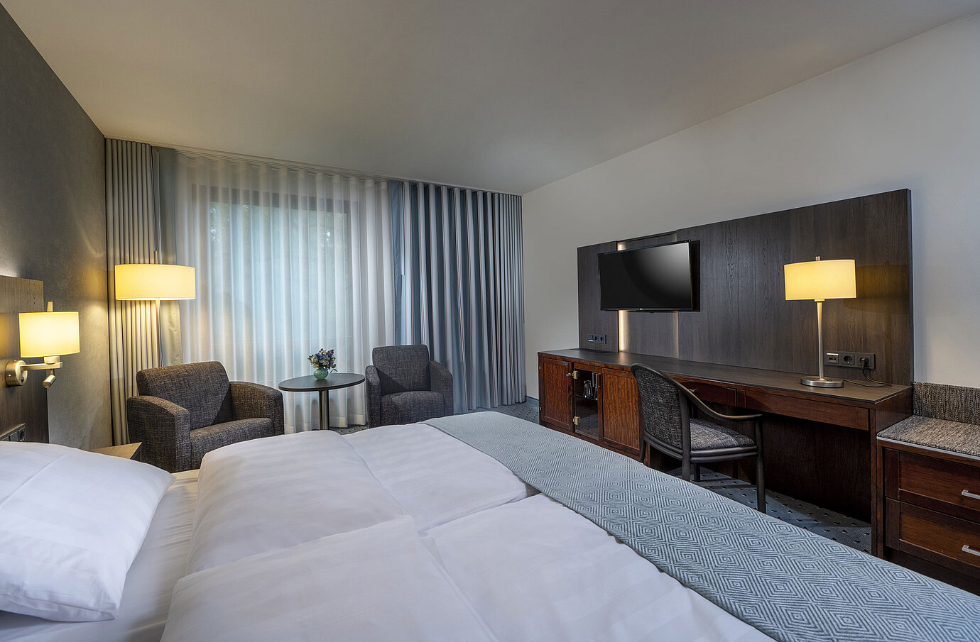 Modernly furnished Classic room with desk, TV, seating area, and comfortable bed at Maritim Hotel Bremen.
