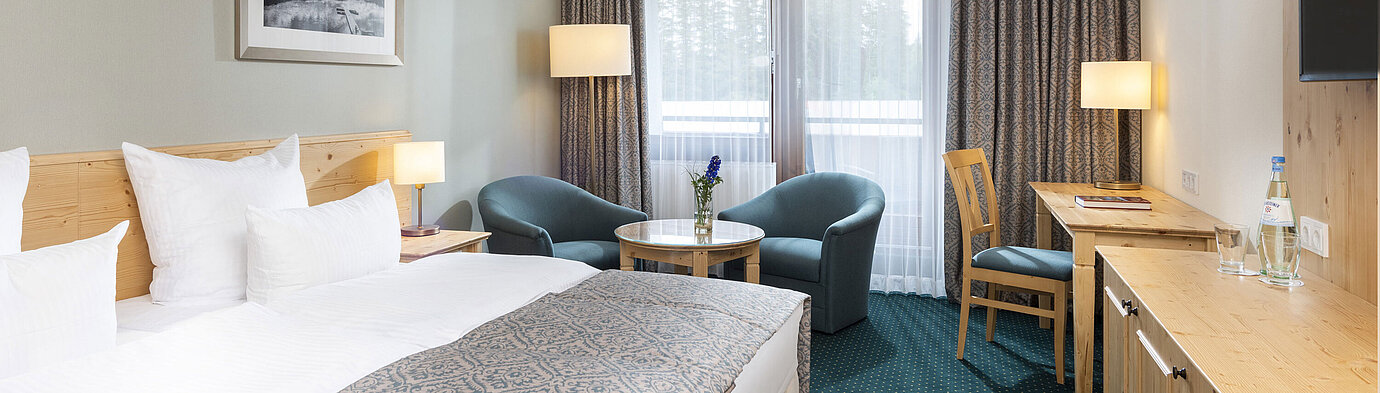 Bright double room at Maritim TitiseeHotel with seating area, desk and forest view