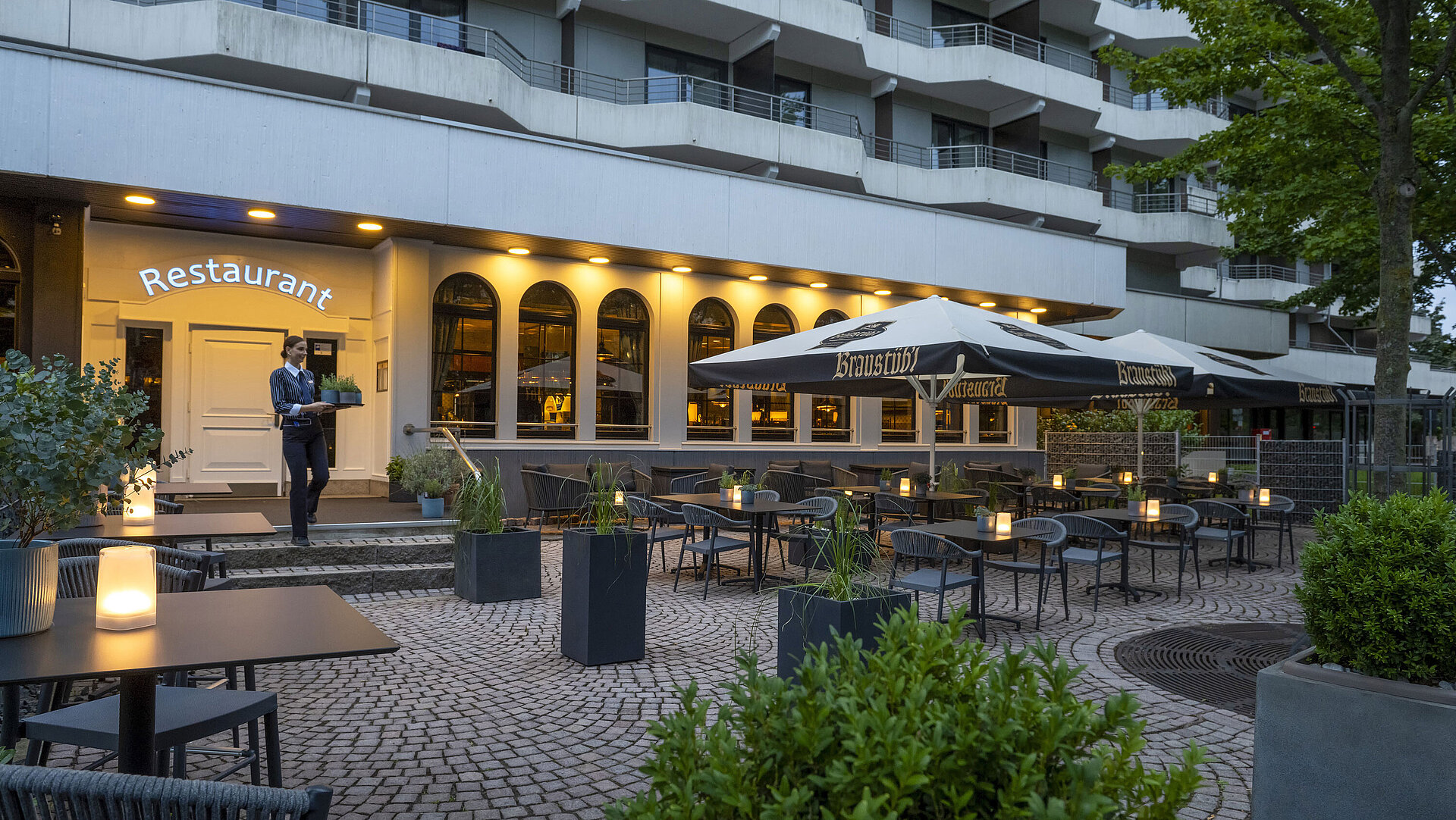 Evening atmosphere on the terrace of the Maritim Hotel Darmstadt with a staff member carrying a tray to the restaurant.