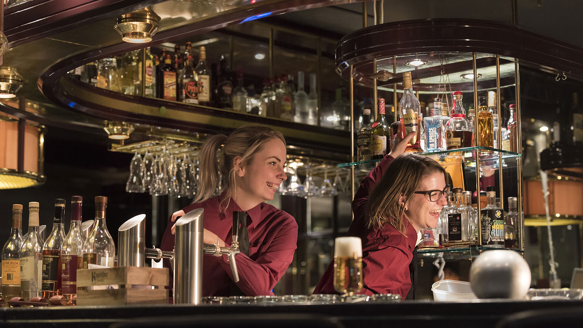 Camareros en el piano bar del Hotel Maritim Bonn, rodeados de una amplia selección de licores y bebidas.