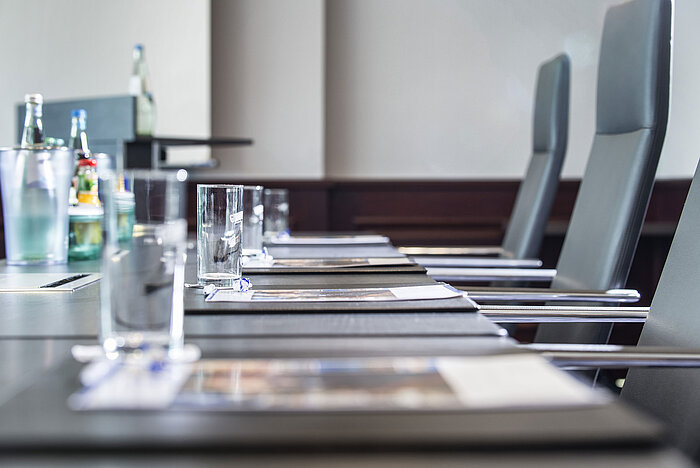 Primer plano de una mesa de conferencia elegante con vasos y blocs de notas.
