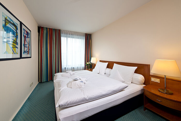 Chambre de la suite principale à l'hôtel Maritim Frankfurt avec lit double, mobilier moderne et ambiance relaxante.