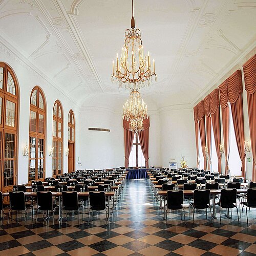 Sala eventi elegante al Maritim Hotel Fulda con lampadari, finestre alte e posti a sedere raffinati per eventi.