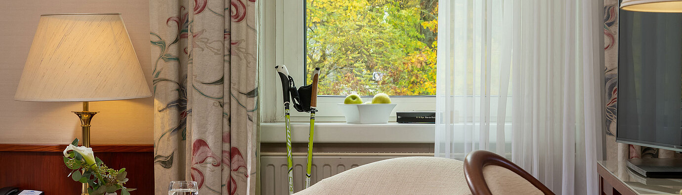 Angolo salotto della camera Classic singola con poltrona, tavolino, lampada e vista dalla finestra al Maritim Hotel Bad Wildungen.