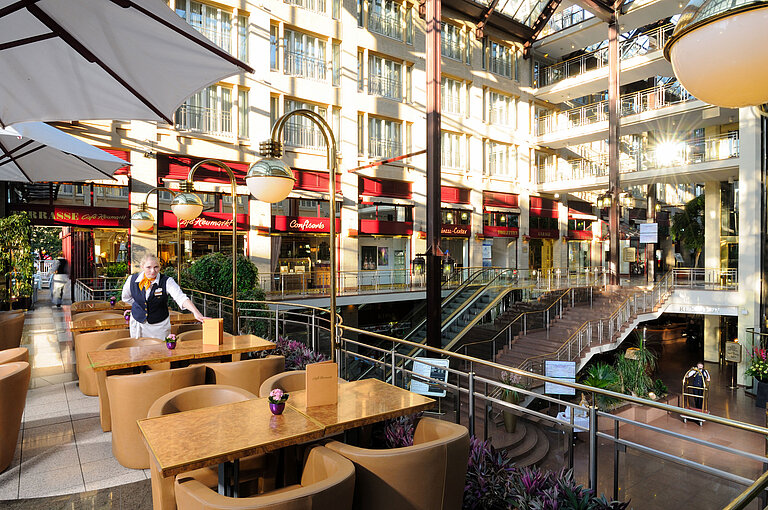 Café Heumarkt en el Hotel Maritim Colonia con asientos y personal de servicio en un ambiente elegante.