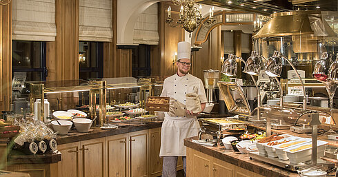 Buffet de desayuno en el restaurante "Rôtisserie" del Maritim Hotel Bonn con una variedad de platos y un chef amable.