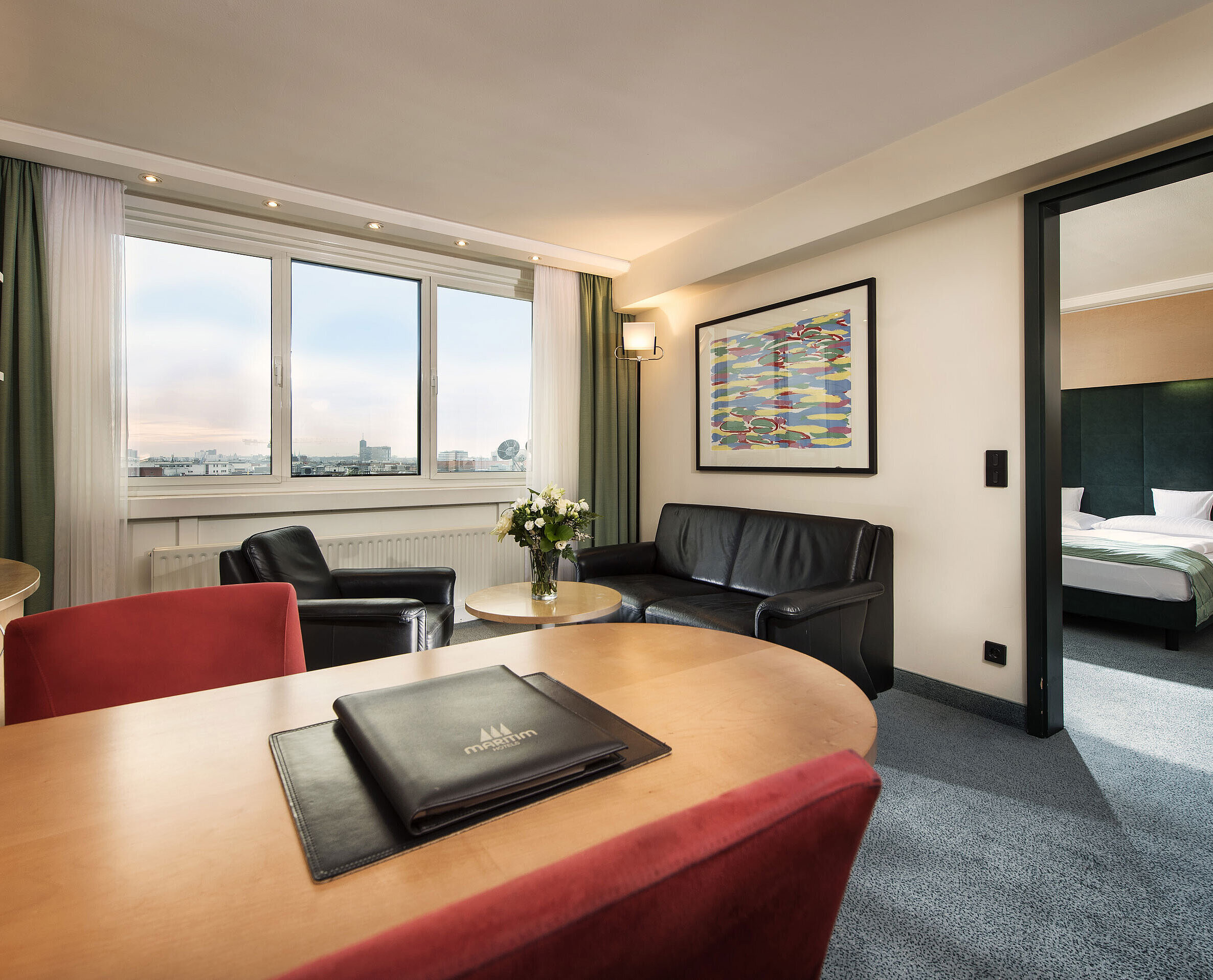 Junior suite at Maritim proArte Hotel Berlin with living area, desk, sofa, and separate bedroom with king-size bed.